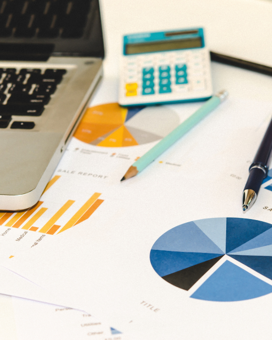 Image of printed report documents, showing pie charts with a calculator and a pencil nearby